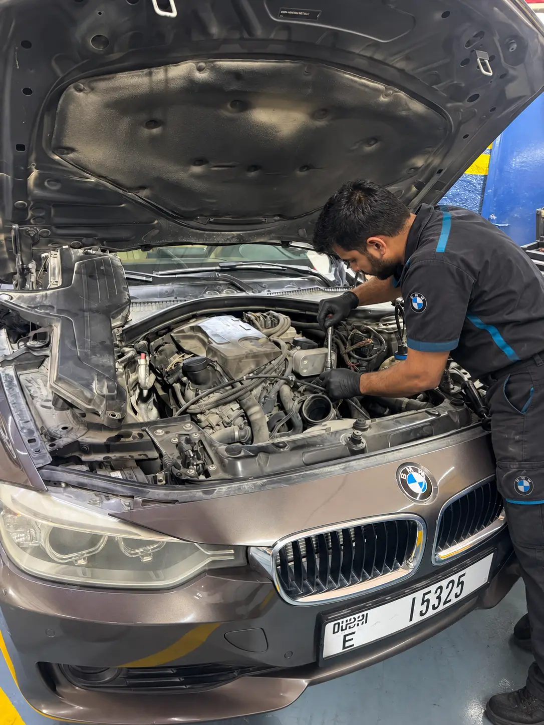 فني يعمل بأداة على محرك BMW بنية والغطاء مفتوح